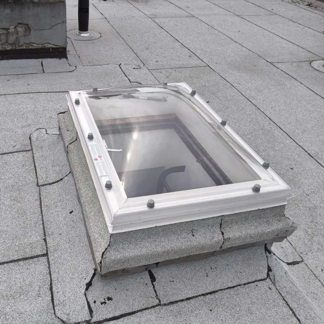 Nieuwe heldere lichtkoepel geplaatst op bestaande gemetselde opstand op plat dak